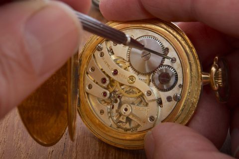 hands that repair an old pocket watch